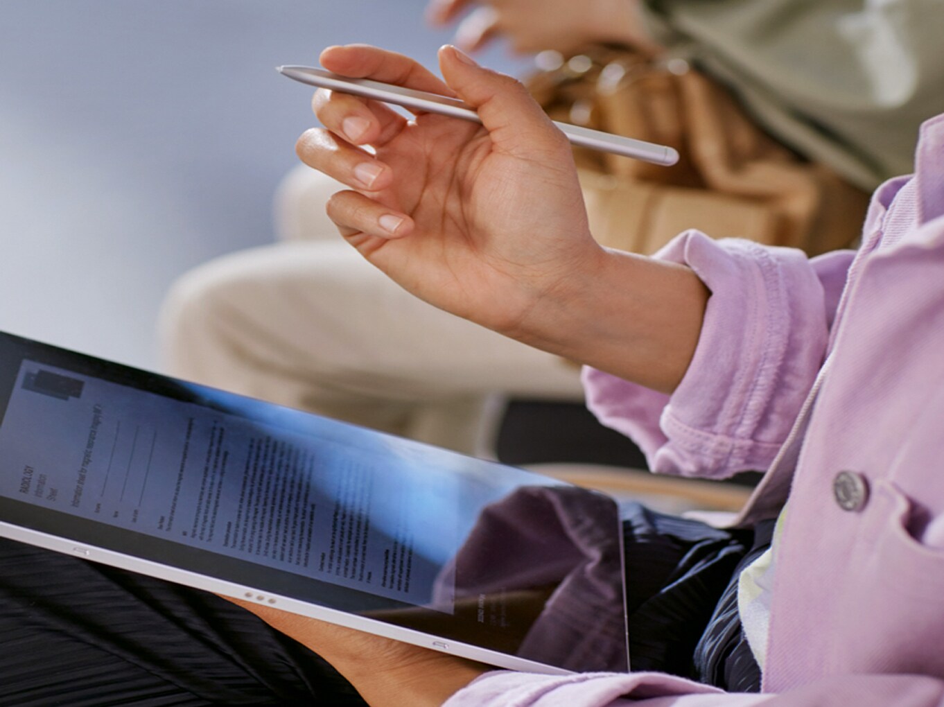 image shows woman in waiting room with digital registration on a tablet